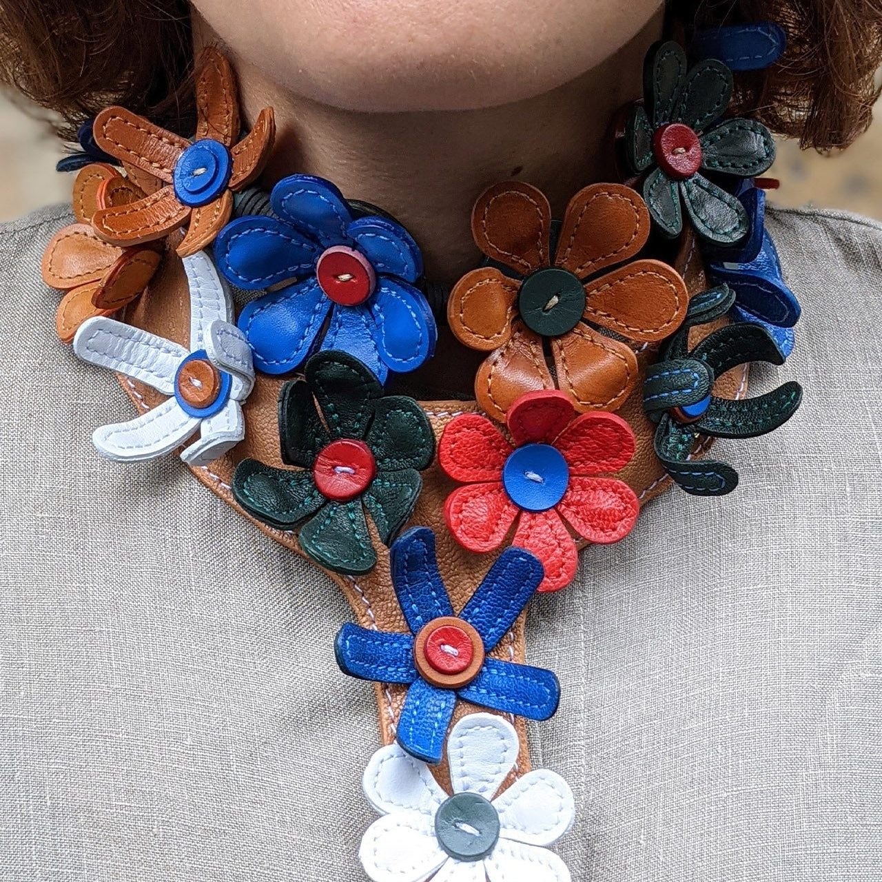 Colorful floral-patterned leather necklace on a person wearing a gray shirt.